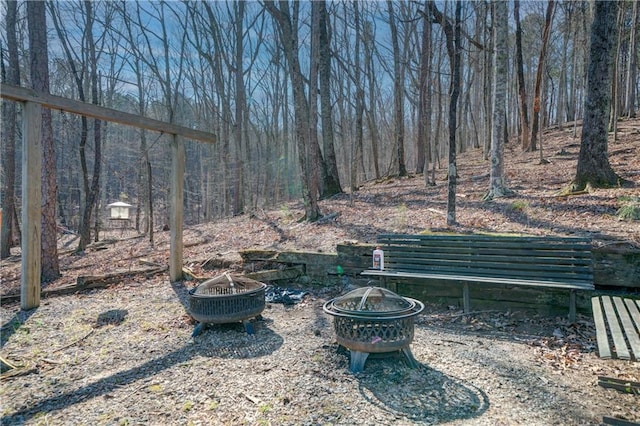 view of yard featuring an outdoor fire pit and a view of trees