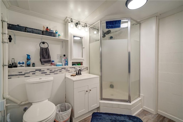 bathroom featuring toilet, wood finished floors, vanity, a shower stall, and tasteful backsplash