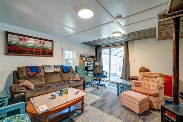 carpeted living area featuring concrete block wall