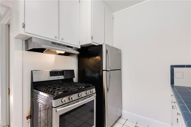 kitchen with light tile patterned flooring, appliances with stainless steel finishes, tile counters, and white cabinets