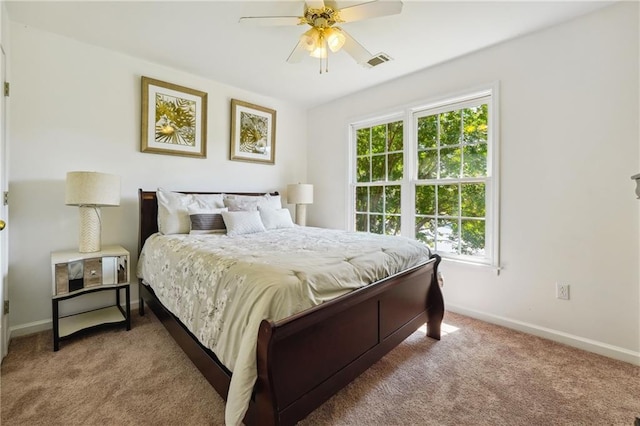 carpeted bedroom featuring a ceiling fan, visible vents, and baseboards