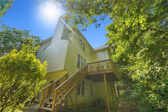 rear view of house featuring stairs, a chimney, a deck, and cooling unit