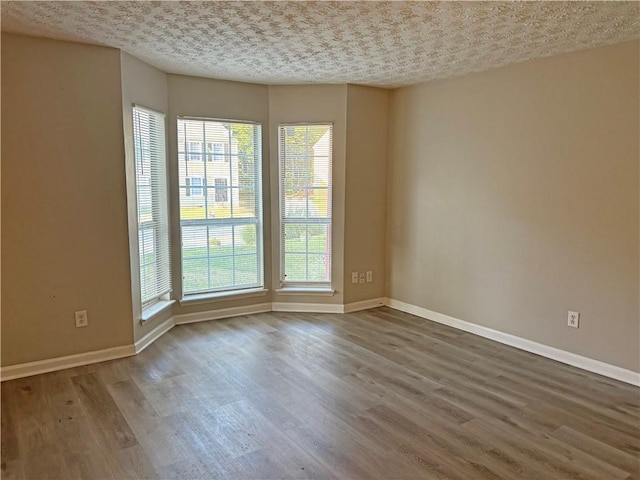 unfurnished room with a textured ceiling and hardwood / wood-style floors