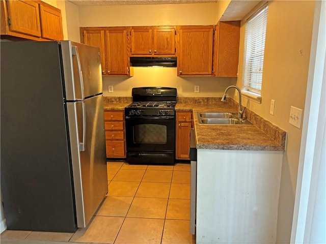 kitchen featuring light tile patterned flooring, sink, black gas stove, and stainless steel fridge