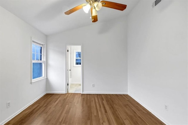 empty room with ceiling fan, hardwood / wood-style floors, and vaulted ceiling