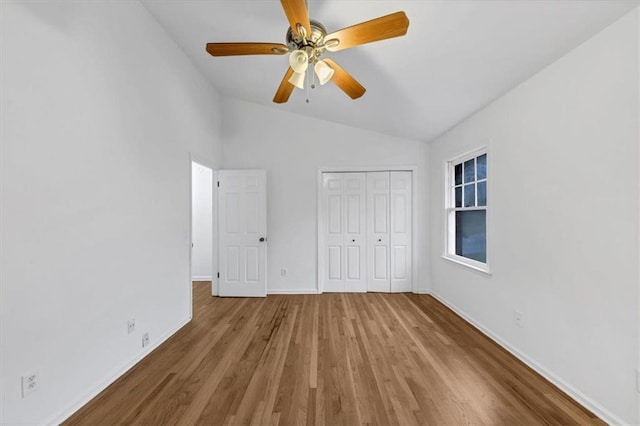 unfurnished bedroom with vaulted ceiling, ceiling fan, a closet, and hardwood / wood-style floors