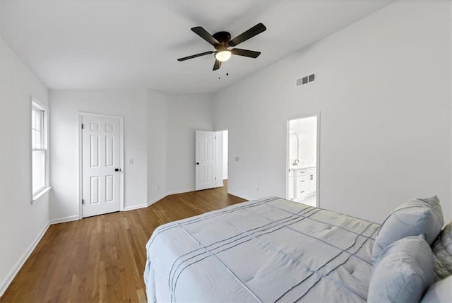 bedroom with vaulted ceiling, ensuite bath, a closet, wood-type flooring, and ceiling fan