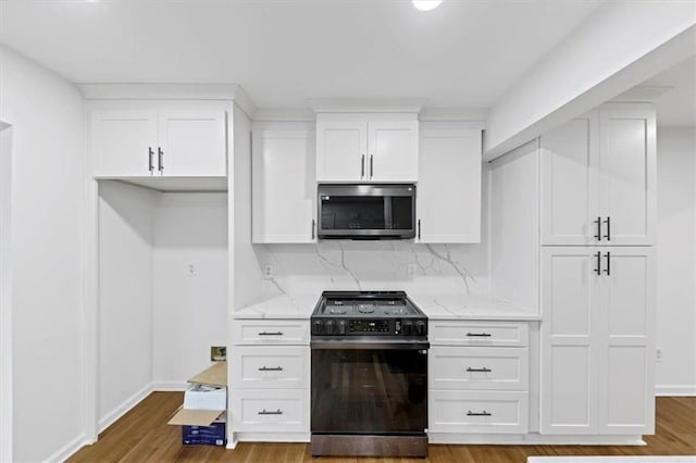 kitchen with light stone counters, white cabinetry, stove, and light hardwood / wood-style flooring