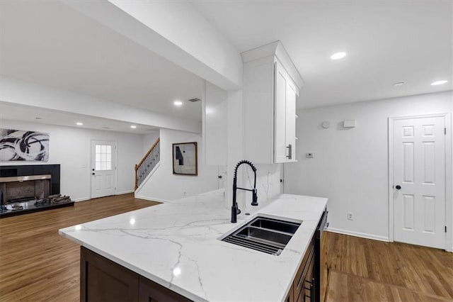 kitchen featuring sink, white cabinetry, light stone counters, and dark hardwood / wood-style floors