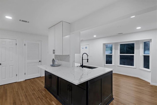 kitchen featuring sink, white cabinets, light hardwood / wood-style floors, and light stone counters