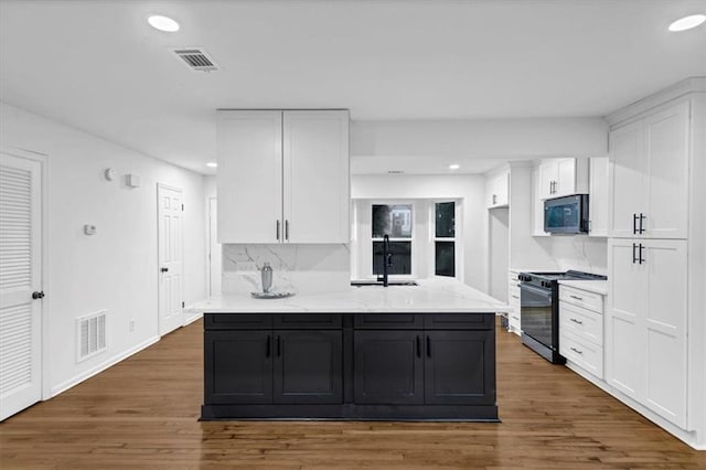 kitchen with sink, white cabinetry, gas range oven, tasteful backsplash, and light stone countertops