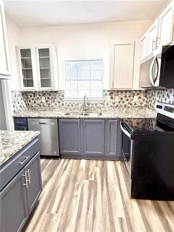 kitchen with light hardwood / wood-style floors, white cabinetry, sink, and appliances with stainless steel finishes