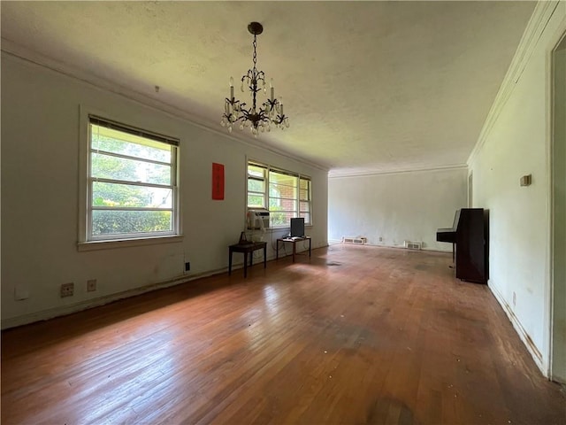 unfurnished living room featuring ornamental molding, a notable chandelier, and hardwood / wood-style floors