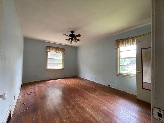 empty room with visible vents, ceiling fan, a healthy amount of sunlight, and hardwood / wood-style floors