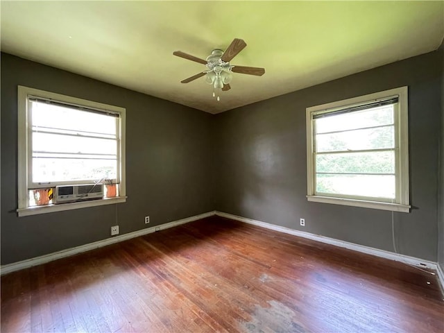 unfurnished room featuring baseboards, cooling unit, a healthy amount of sunlight, and hardwood / wood-style flooring