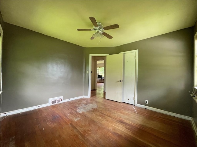unfurnished bedroom with a ceiling fan, baseboards, visible vents, and wood finished floors