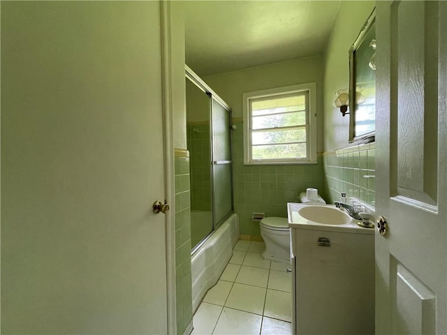 bathroom featuring tile patterned flooring, enclosed tub / shower combo, toilet, and vanity