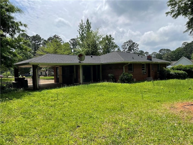 view of front of home with an attached carport, brick siding, fence, and a front lawn