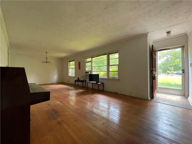 living room featuring ornamental molding, wood-type flooring, a textured ceiling, and a notable chandelier