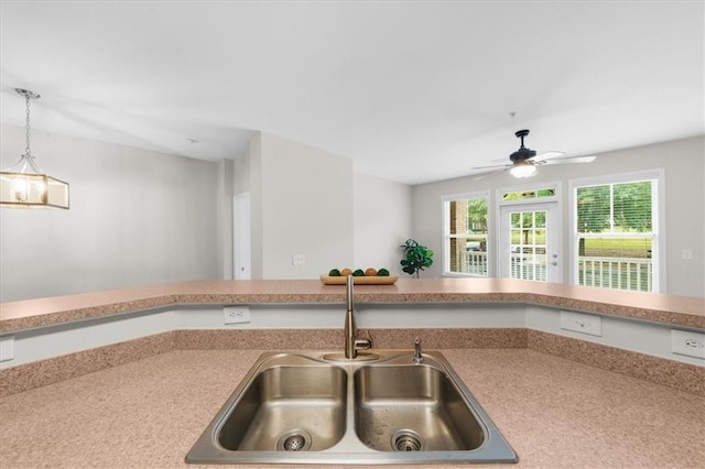 kitchen with pendant lighting, ceiling fan with notable chandelier, and sink