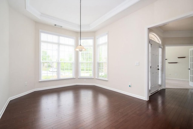 unfurnished dining area featuring crown molding, baseboards, dark wood-type flooring, a tray ceiling, and visible vents