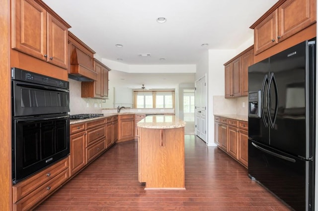 kitchen with a center island, tasteful backsplash, dark wood finished floors, black appliances, and a peninsula