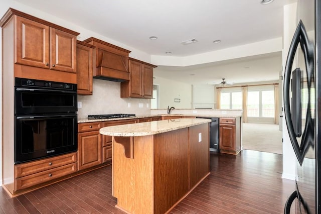 kitchen with visible vents, a peninsula, dark wood-style floors, a center island, and black appliances