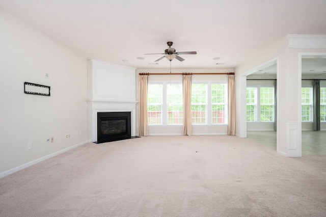 unfurnished living room featuring baseboards, a fireplace with flush hearth, ceiling fan, and light colored carpet
