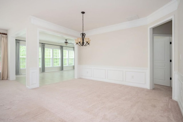 empty room featuring wainscoting, a chandelier, light carpet, and ornamental molding