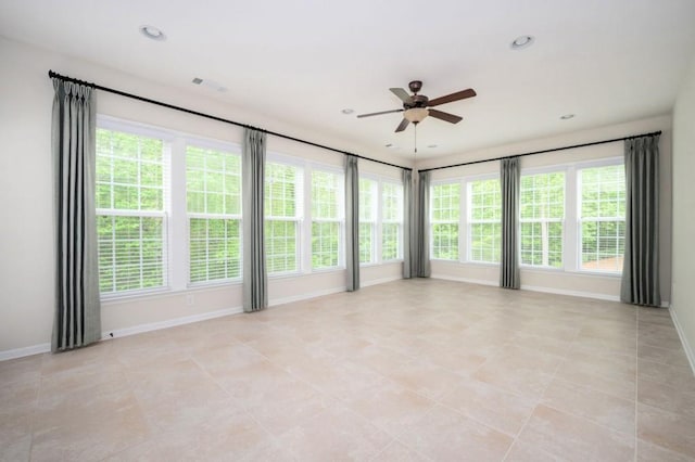 empty room featuring baseboards, plenty of natural light, and ceiling fan