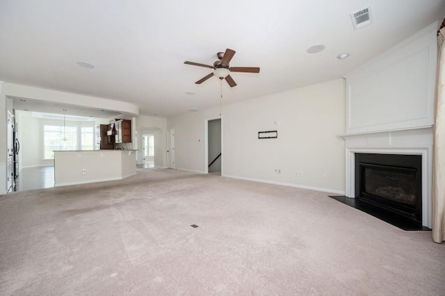 unfurnished living room featuring ceiling fan, light carpet, baseboards, a fireplace with flush hearth, and visible vents