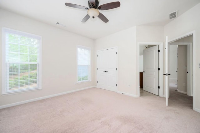 unfurnished bedroom featuring baseboards, light carpet, a ceiling fan, and visible vents