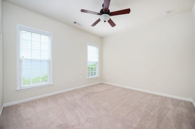 empty room featuring baseboards, carpet, a healthy amount of sunlight, and visible vents