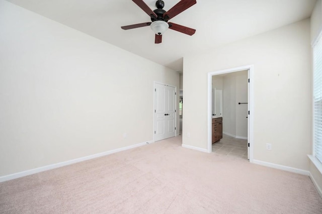 unfurnished bedroom with baseboards, ensuite bathroom, light carpet, and a closet