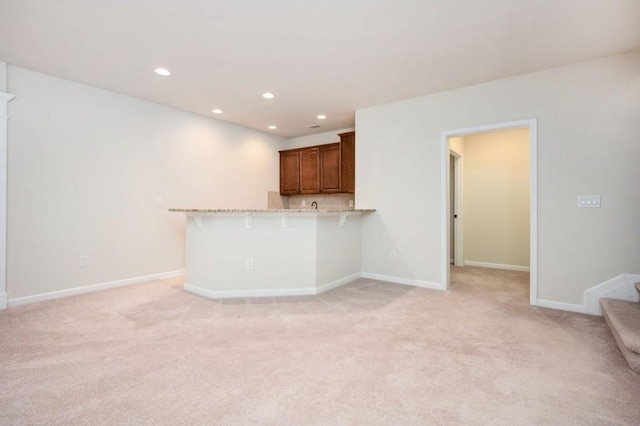 unfurnished living room featuring recessed lighting, baseboards, and light colored carpet