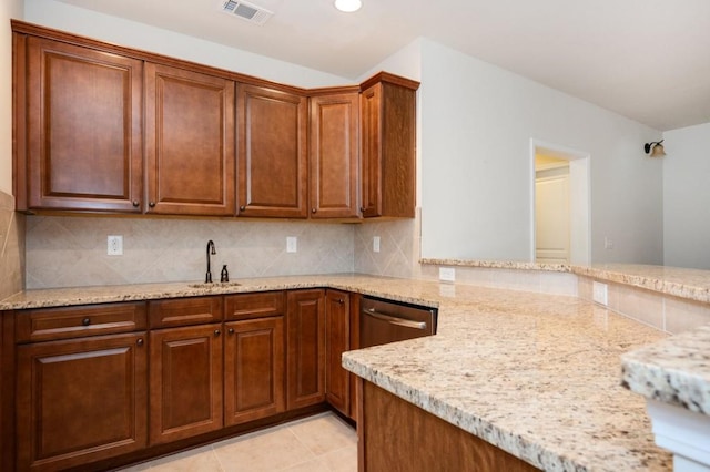 kitchen with a sink, tasteful backsplash, light stone countertops, and visible vents