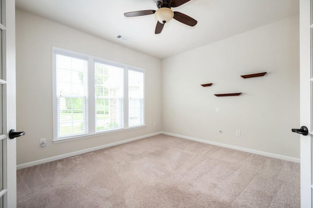 carpeted spare room featuring baseboards, a ceiling fan, and visible vents