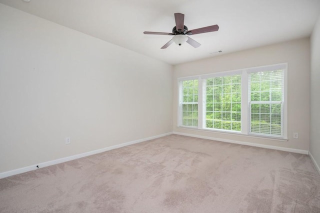 carpeted spare room featuring a ceiling fan and baseboards