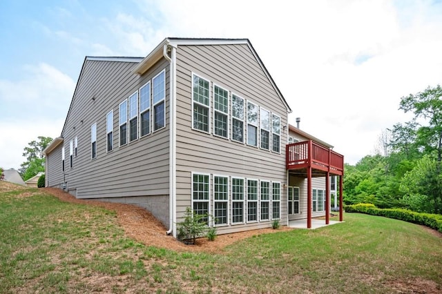 back of house with a lawn, a wooden deck, and a patio area