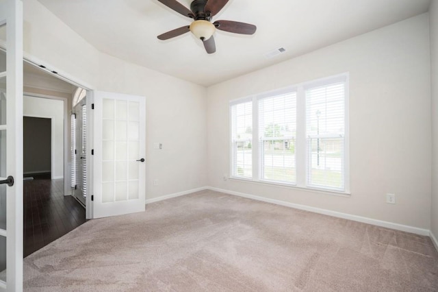 carpeted empty room with a ceiling fan, baseboards, visible vents, and french doors