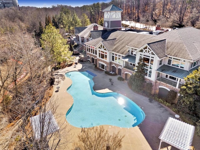 pool with a patio area and a wooded view