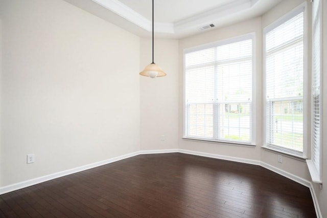 unfurnished dining area with visible vents, ornamental molding, baseboards, dark wood-type flooring, and a tray ceiling