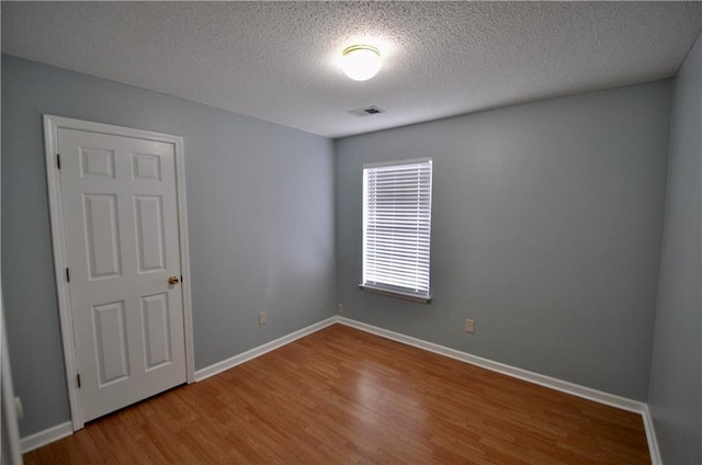 unfurnished room with wood-type flooring and a textured ceiling