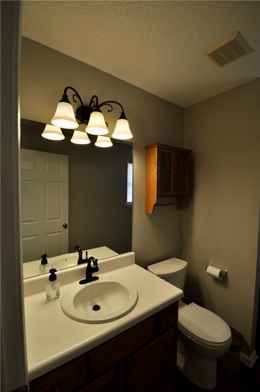 bathroom featuring vanity, a textured ceiling, and toilet