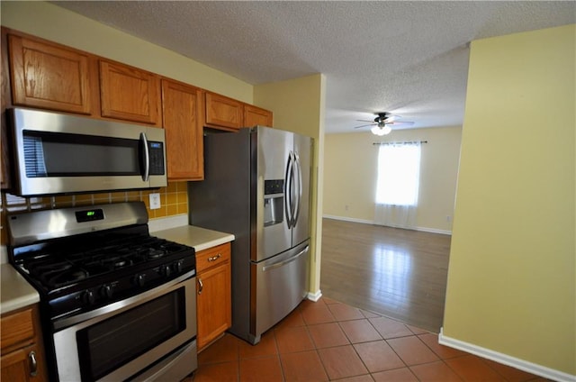 kitchen featuring ceiling fan, tasteful backsplash, a textured ceiling, light tile patterned floors, and appliances with stainless steel finishes