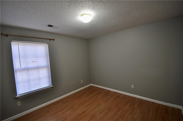 unfurnished room with hardwood / wood-style floors and a textured ceiling