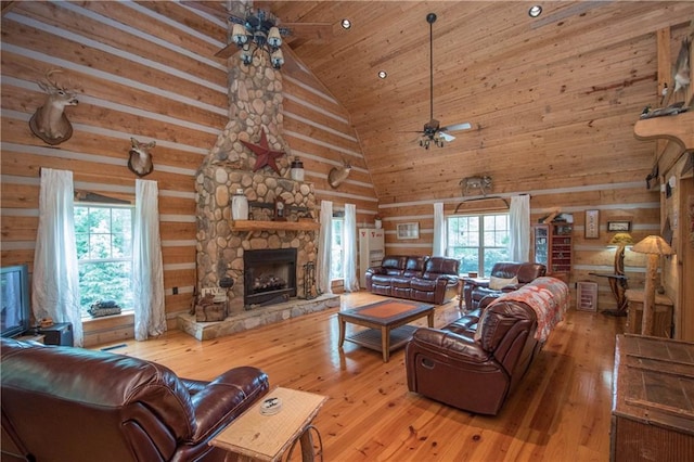 living room featuring high vaulted ceiling, light hardwood / wood-style flooring, a fireplace, and plenty of natural light