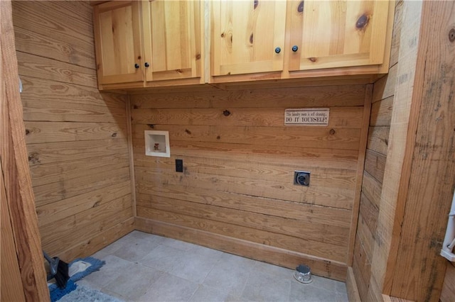 washroom with light tile flooring, wooden walls, cabinets, hookup for an electric dryer, and hookup for a washing machine