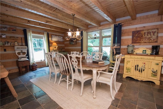 dining space with beam ceiling, dark tile floors, a wealth of natural light, and a chandelier