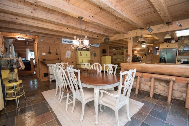 tiled dining room featuring wooden walls, wooden ceiling, ceiling fan with notable chandelier, and beamed ceiling